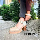 Sandalia de cuero modelo Berlin, con plataforma y taco ancho de madera, punta cuadrada y tira ajustable al tobillo con hebilla metálica.