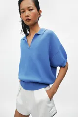 Polo amplio de punto color celeste, con cuello y escote en V, de manga corta.