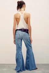 Pantalón jean de corte flare y tiro medio, color celeste con efecto lavado, de diseño amplio en la parte inferior y dobladillo deshilachado.