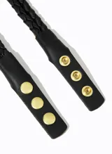 Cinturón negro trenzado de cuero, con hebilla rectangular dorada con piedra negra.
