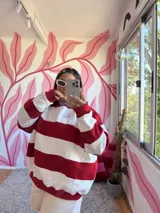 Buzo deportivo a rayas horizontales rojas y crudas, con cuello redondo celeste y logo bordado en el pecho.