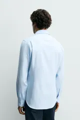 Camisa de corte regular fit confeccionada en tejido de algodón con textura. Presenta cuello italiano, manga larga con puños abotonados y cierre frontal de botones.