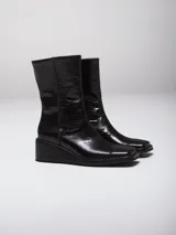 Bota de caña media en color negro con textura efecto cocodrilo y taco cuña.