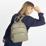 Mochila de tamaño mediano confeccionada en símil cuero color beige, con doble bolsillo frontal con cierre metálico, asa de mano superior y correas regulables de cinta tejida.