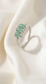 Anillo de plata 925 con tres piedras ovales de esmeralda y pequeños detalles de zirconía en los laterales.