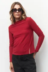 Remera roja de manga larga con cuello alto y corte diagonal en la parte inferior.