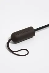 Paraguas plegable marrón con estampado gráfico blanco y negro, mango negro con relieve de la marca y funda a juego.