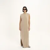 Vestido largo color beige, sin mangas, con cuello redondo y abertura lateral en el ruedo.