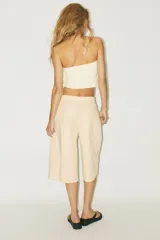 Top bandeau color crema con escote recto, hombros descubiertos y detalle de volantes en capas.