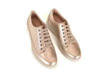 Championes de cuero metalizado en tono dorado, con diseño de cordones y suela plana de goma en color crema.