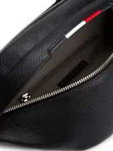 Riñonera negra de poliuretano granulado con cierre de cremallera, correa ajustable de textil trenzado con cierre de apertura fácil, bolsillo interior con cremallera, cinta distintiva y logo metálico de Tommy Hilfiger en la parte delantera.