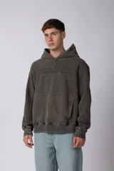 Buzo canguro oversize de friza pesada con efecto lavado desgastado. Presenta diseño con recortes, capucha amplia y puños acanalados.
