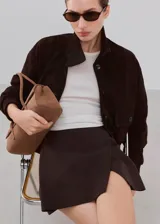 Minifalda marrón oscuro de corte recto, con diseño liso y cierre cruzado simulado.