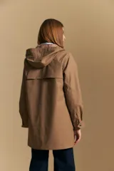 Pilot de largo medio color azul marino, con capucha integrada, cierre frontal oculto y bolsillos aplicados con tapa. Presenta una silueta recta y diseño funcional.