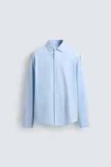 Camisa de corte regular fit confeccionada en tejido de algodón con textura twill. Presenta cuello italiano, manga larga con puños abotonados y cierre frontal de botones.