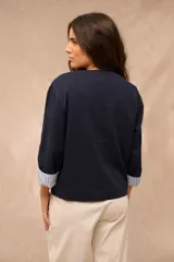 Campera azul marino de corte recto, con cuello redondo, cierre frontal con botones oscuros, bolsillos frontales con solapa en el pecho y mangas largas con vuelta estampada a rayas.