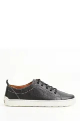 Championes de cuero negro con textura granulada, diseño de corte bajo, costuras decorativas en contraste y suela de goma blanca.