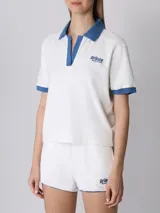 Remera polo deportiva Prince de rizo blanca con cuello y mangas en azul. Fabricada en Portugal con 100% algodón, mangas y dobladillo inferior acanalados, cuello abierto y corte cuadrado.
