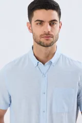 Camisa de manga corta confeccionada en mezcla de lino y algodón, color beige, con cuello camisero abotonado, bolsillo frontal en el pecho y cierre de botones.