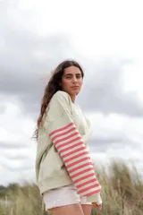 Buzo color verde claro con mangas largas a rayas horizontales rosas y blancas.