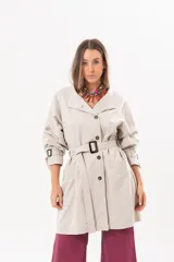 Trench de gabardina Tencel color beige, de silueta relajada, con cierre frontal de botones, lazo desmontable y regulable en la cintura, bolsillos amplios y lazos en los puños.