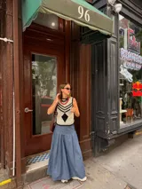 Falda larga negra con diseño de caderín y tablas.