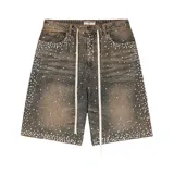 Short de jean con corte baggy, color verde lavado con efecto desgastado. Presenta una profusa decoración de perlas y brillantes incrustados en toda la superficie, con cordones largos en la cintura.