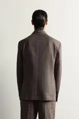 Blazer regular fit de Zara, confeccionada en tejido de lino y lana con diseño a cuadros en tonos marrones y grises. Cuenta con solapas de muesca, cierre frontal de un botón y bolsillos con solapa en la cadera.