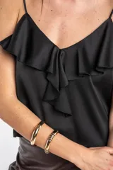 Musculosa negra de satén con escote en V, tirantes finos y detalle de volados en el pecho.
