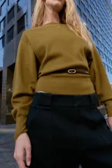 Jersey de punto color mostaza con cuello barco, manga larga con sisa ancha y detalle de cinturón fino integrado en la cintura.