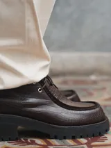 Zapato de cuero negro con cordones, detalle de pespuntes en la puntera y suela de goma con plataforma.