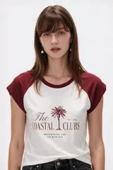 Remera al cuerpo con diseño raglán, color blanco en el torso y azul marino en las mangas cortas y el cuello. Cuenta con un estampado frontal de temática de tenis con las inscripciones "Portofino Tennis" y "Summer Italia".