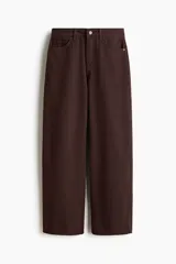 Pantalón tipo jean de corte wide leg y tiro medio, confeccionado en denim de algodón rígido color marrón oscuro. Presenta diseño clásico de cinco bolsillos, cierre frontal con botón y cremallera, y piernas amplias con caída recta.