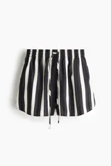 Short de tiro alto confeccionado en tejido dobby con patrón de rayas verticales en blanco y negro. Cuenta con cintura elástica fruncida, cordón ajustable y bajo redondeado.