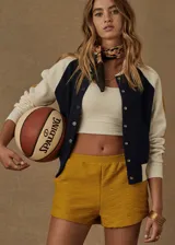 Campera bomber azul marino con mangas color crema con rayas mostaza. Tiene cuello, puños y ruedo acanalados, cierre frontal con botones a presión y corte holgado.