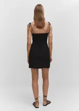 Vestido corto de corte recto confeccionado en mezcla de lino y viscosa. Presenta cuello recto, tirantes finos ajustables con lazo y detalle de abalorios en los laterales del escote. Incluye cierre lateral de cremallera y forro de algodón.