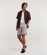 Bermuda masculina de sarga gris claro, con cintura elástica, cordón ajustable blanco, bolsillos laterales y estampa rayada sutil.