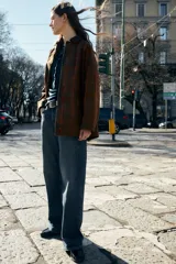 Chaqueta de mujer de la colección Zara Woman, confeccionada en algodón 100% con acabado encerado. Presenta un estampado a cuadros en tonos marrón y rojo, cuello solapa de pana, manga larga con puño y botón, bolsillos de plastrón con solapa en el delantero y cierre frontal con botones a presión.