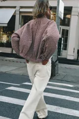 Chaqueta de manga larga con estampado a cuadros vichy en tonos marrón y blanco, cuello camisero, cierre frontal de botones, puños elásticos y cordón ajustable en el bajo.
