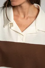 Sweater de tejido de punto con diseño a rayas horizontales en color crema y marrón. Presenta cuello tipo polo con cierre frontal de botones ocultos, mangas largas y un corte oversize.