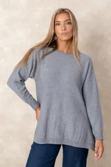 Buzo de punto color gris, con cuello redondo, mangas largas con puños acanalados y diseño de costuras verticales decorativas en el ruedo.