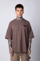 Remera negra de algodón de corte oversize, con mangas cortas y cuello redondo. Estampado pequeño en el frente y diseño grande en la espalda con Mickey Mouse y caracteres orientales en tonos rojizos.