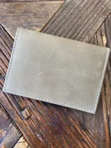 Tarjetero de cuero color gris topo con costuras a tono. Tiene seis ranuras para tarjetas.