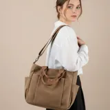 Bolso de lona color marrón con múltiples bolsillos externos frontales y laterales. Posee asas de mano y una correa larga ajustable y extraíble.