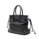 Cartera grande de símil cuero color negro, tipo tote bag, con doble asa de mano y correa larga de tela ajustable. Cuenta con detalles de cordones con nudos en los laterales y el logo metálico de la marca en la parte frontal.