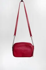 Cartera bandolera negra con diseño capitoneado en forma de V, correa de cuero y cadena plateada, cierre metálico y doble bolsillo interior.