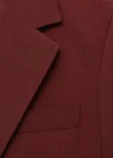 Chaqueta de traje color bordó con solapas de muesca, cierre frontal de un botón, bolsillos con solapa y forro interior.
