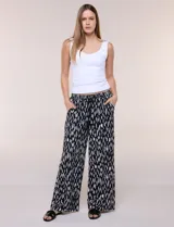 Pantalón de poliéster de corte ancho tipo palazzo y calce relajado, con estampado de hojas en tonos azules, cintura alta elastizada con cordón ajustable y bolsillos laterales.
