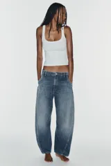 Jeans de tiro medio y corte barrel con diseño de perneras curvadas, tiro medio, trabillas para cinturón y cinco bolsillos. Presenta lavado clásico y costuras pespunteadas decorativas en la parte delantera.