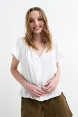 Blusa blanca de manga corta con escote en V y frunce en los hombros, corte holgado y ligero.
